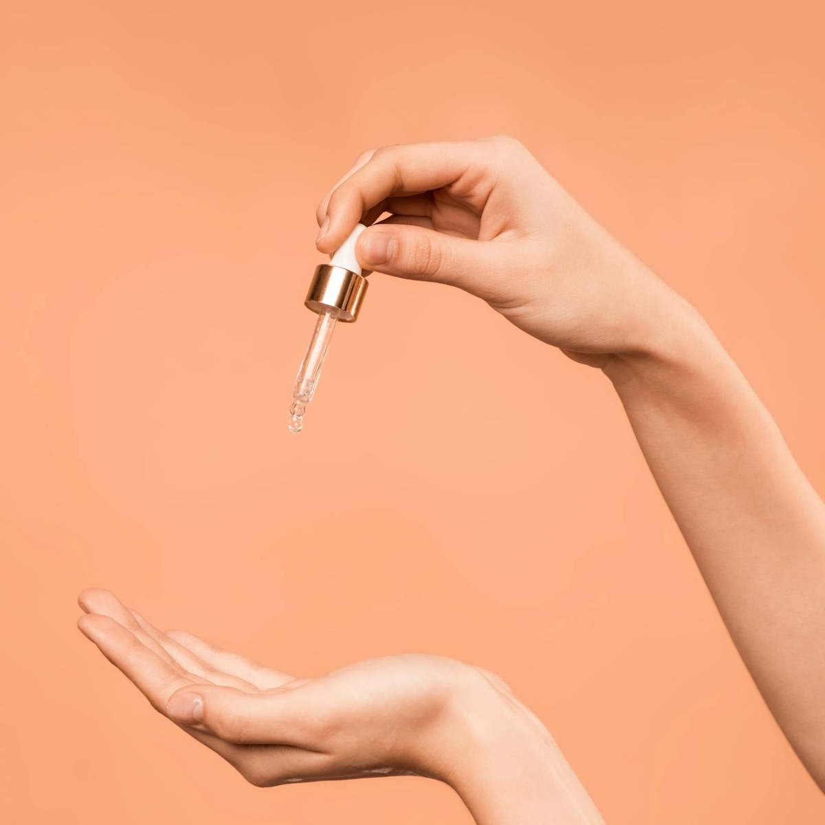 Glass skincare dropper held in hand showing active ingredient application