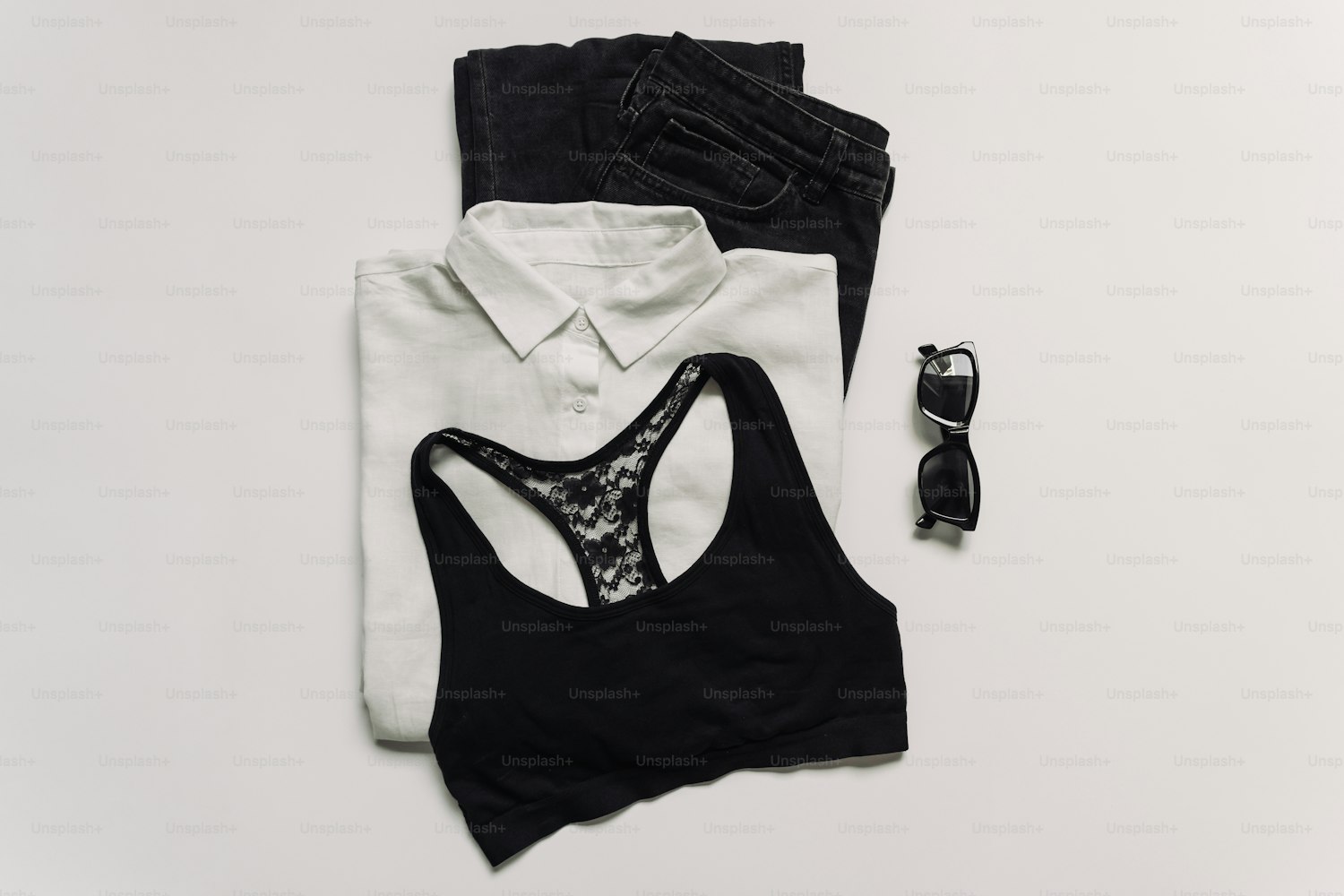 Flat lay of fashion accessories including sunglasses and layered essentials