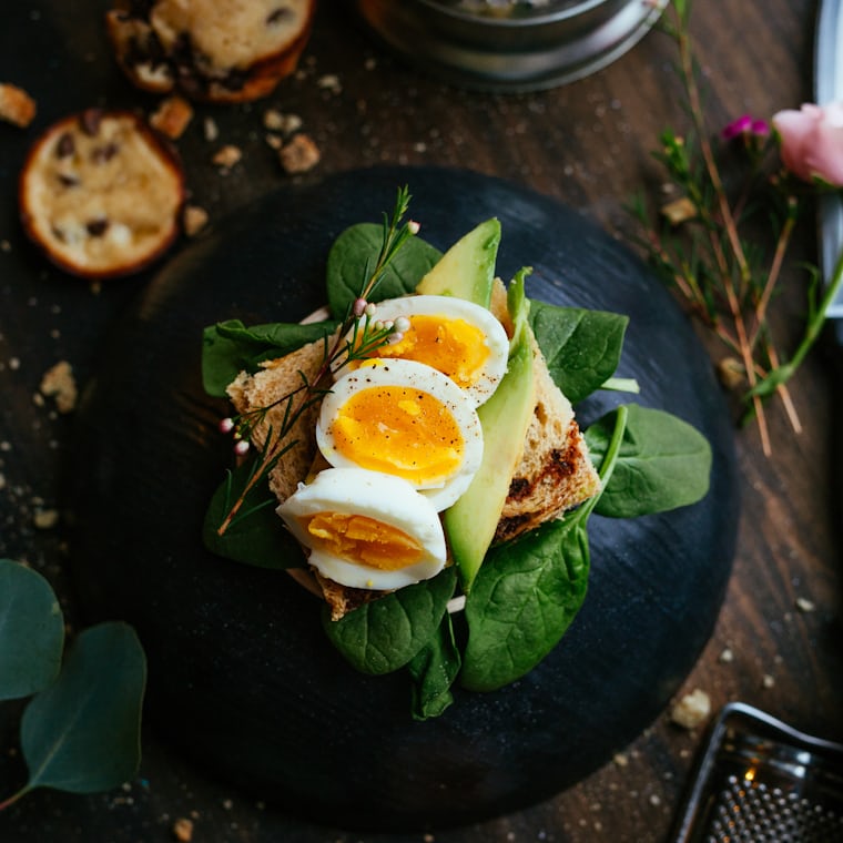 Close-up of fresh healthy breakfast toast with egg and greens on a table
