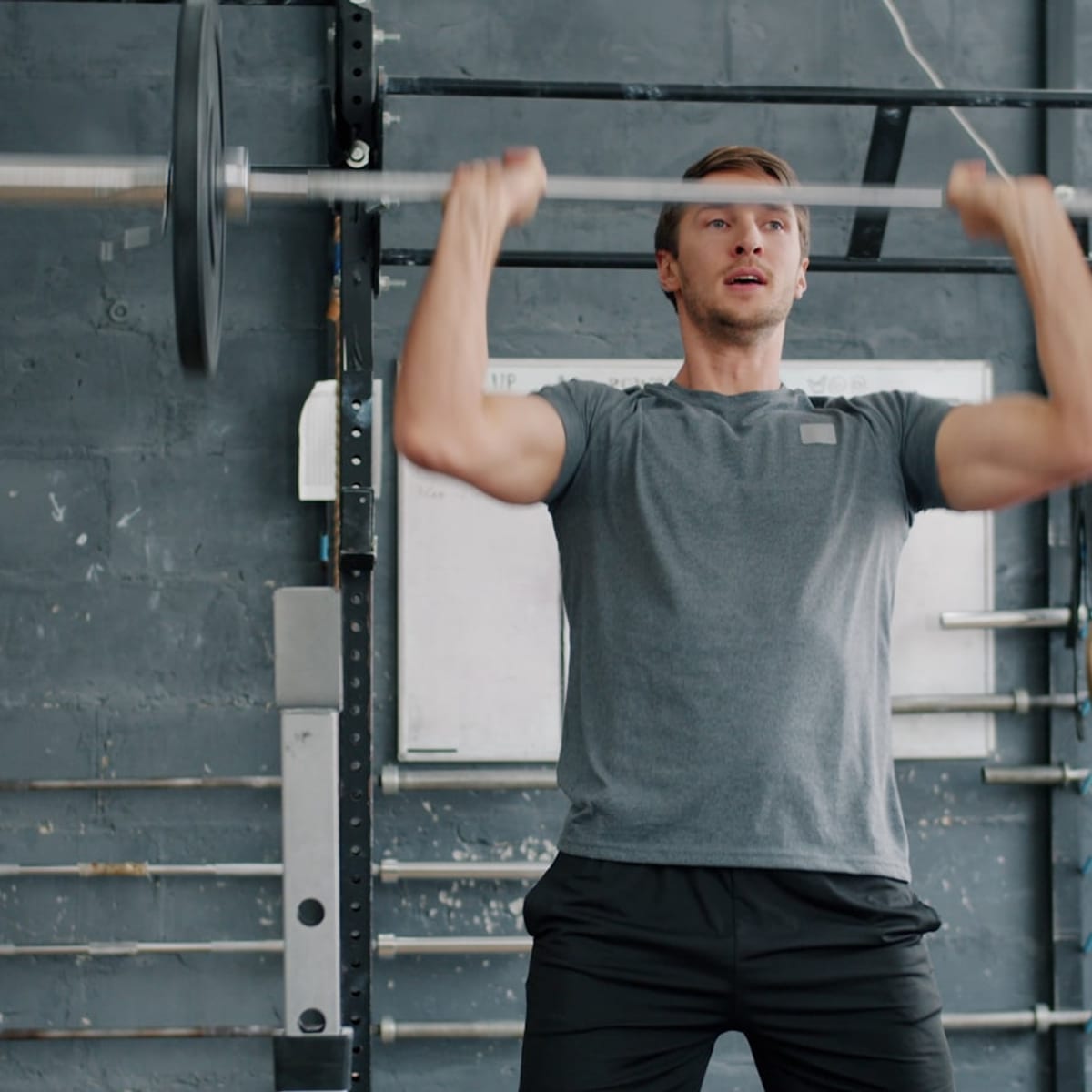Athlete lifting a heavy barbell overhead during strength training in a gym
