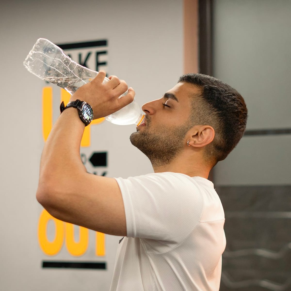 Athlete drinking water in the gym to support hydration and recovery after training