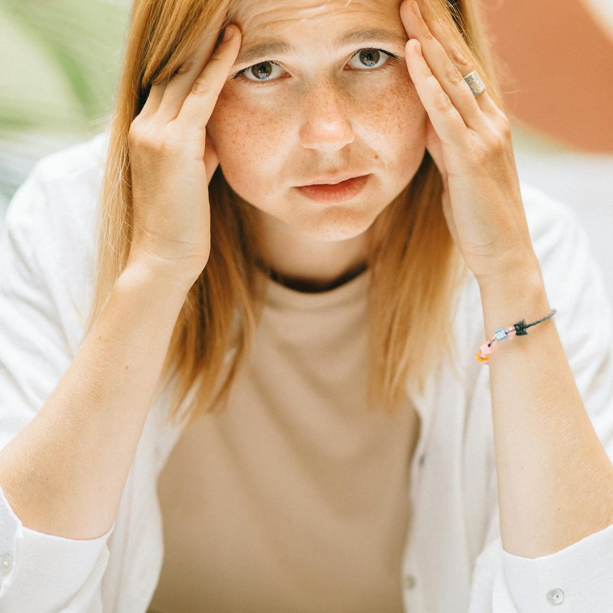 Stressed young woman holding her face, showing emotional overload and fatigue