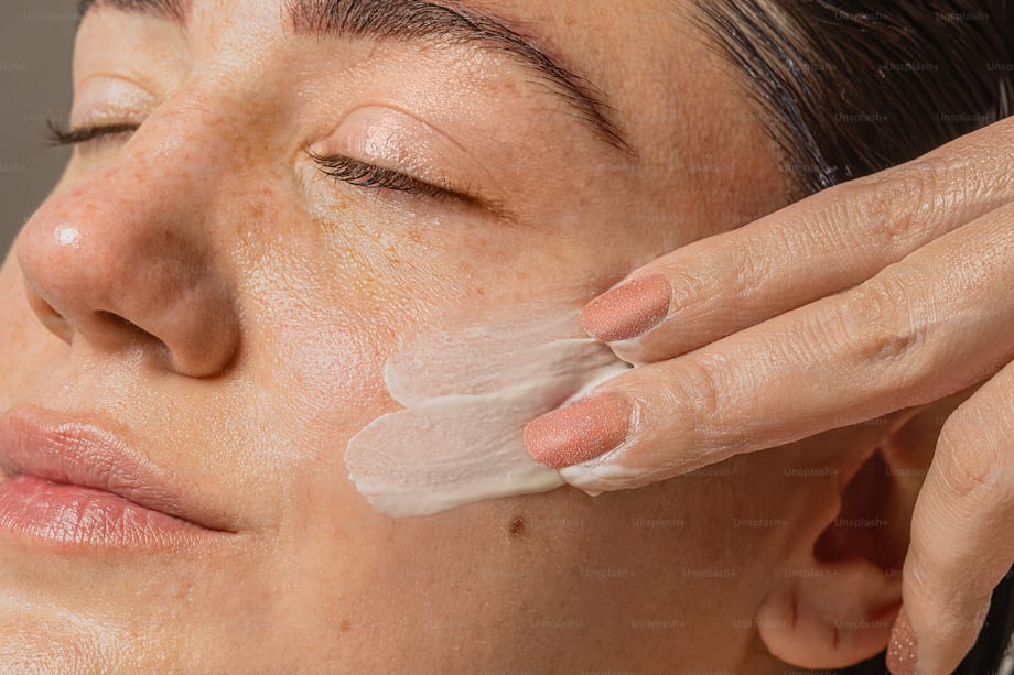 Woman applying facial cream as part of a gentle self-care routine