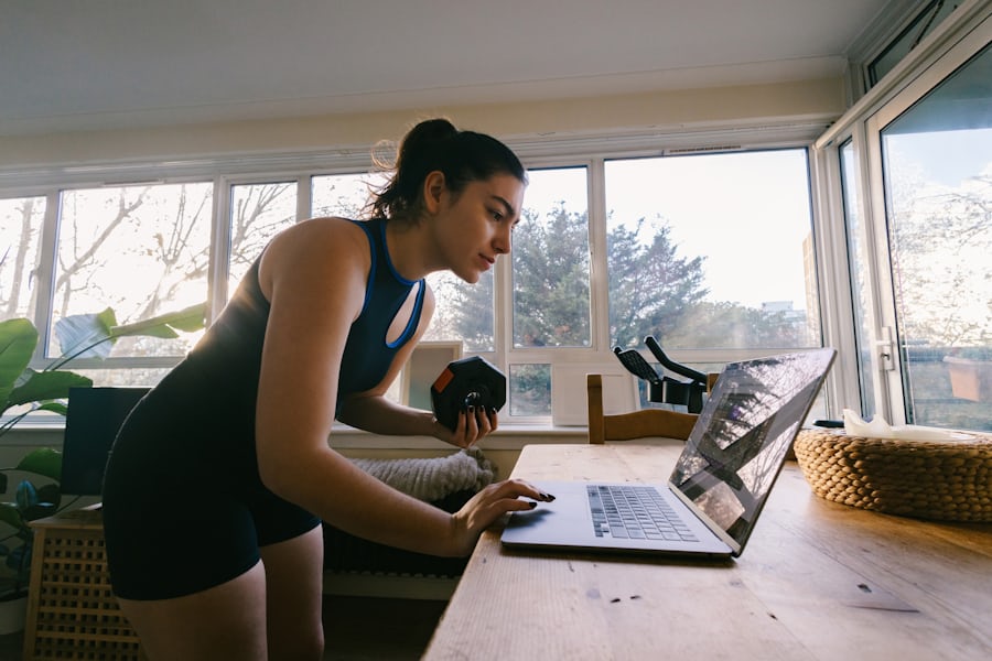 Woman training at home with a dumbbell near a laptop