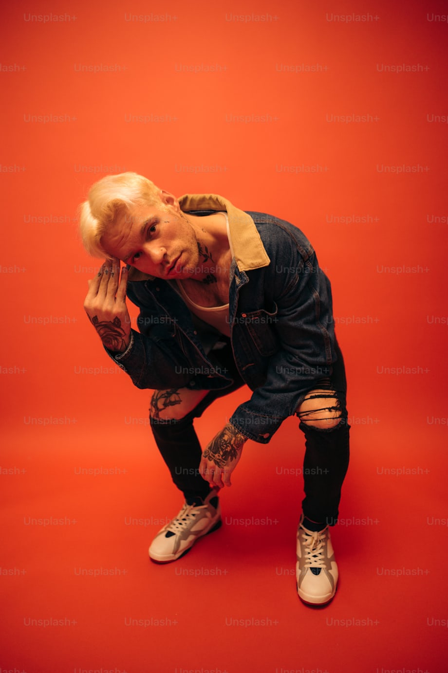 Streetwear look with denim jacket, ripped jeans, and sneakers in studio style