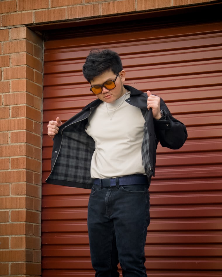 Urban model in black jacket and sunglasses reflecting modern streetwear