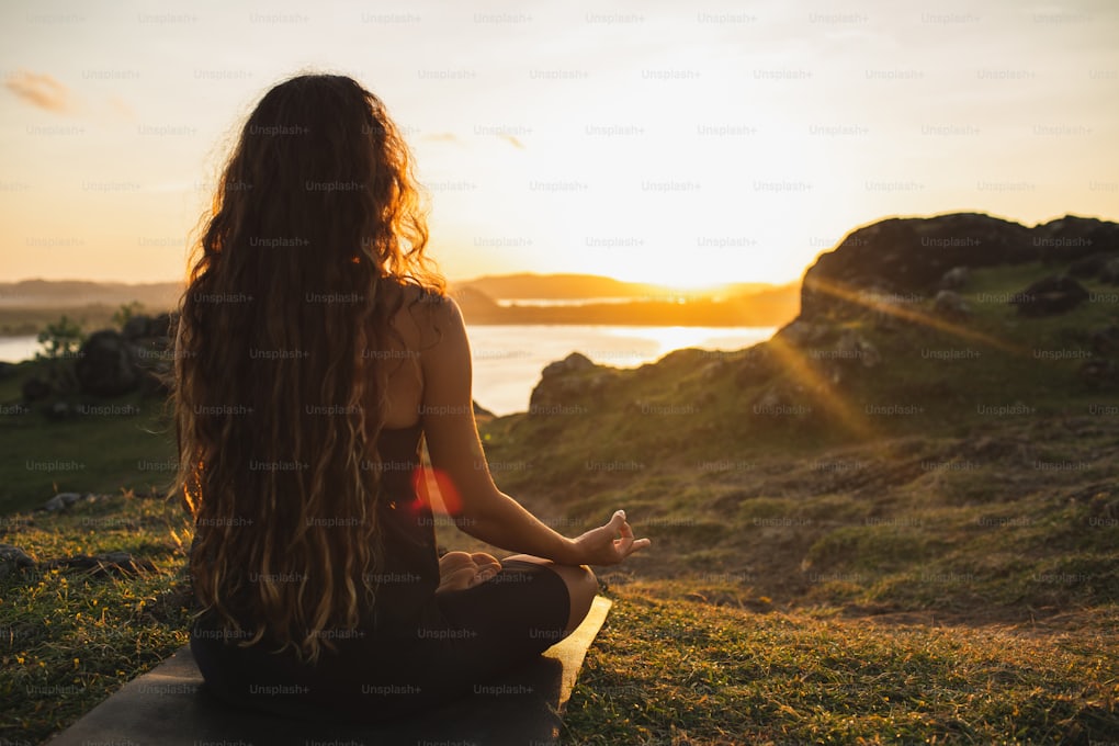 Woman meditating at sunrise in the mountains during a healing retreat