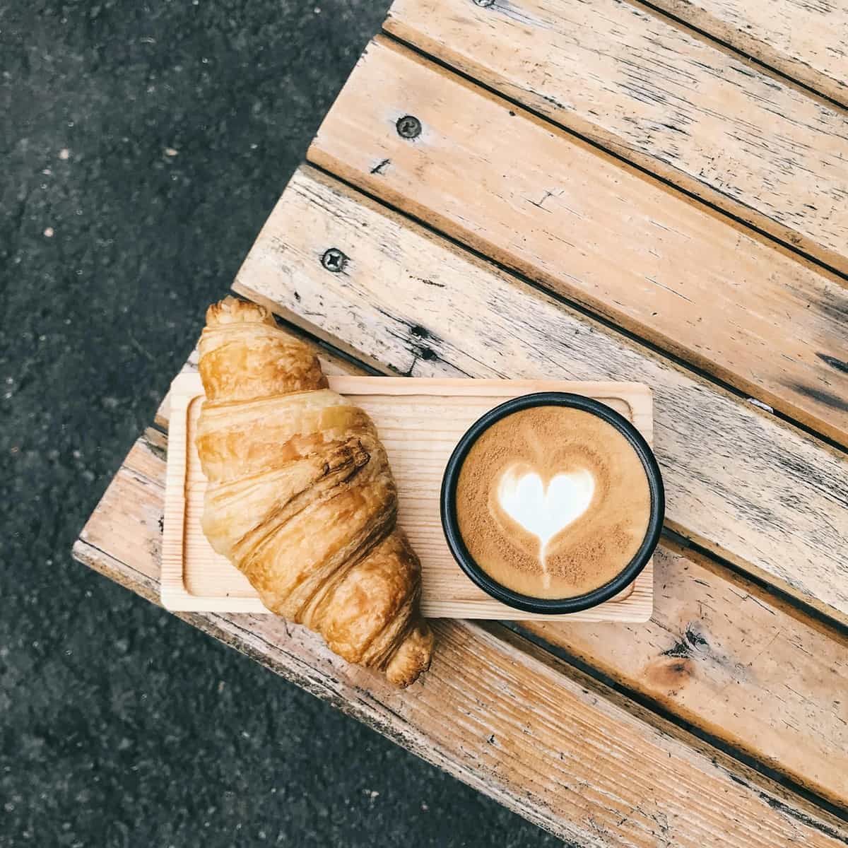 Coffee and croissant on a wooden table representing intentional pause and mindful rest